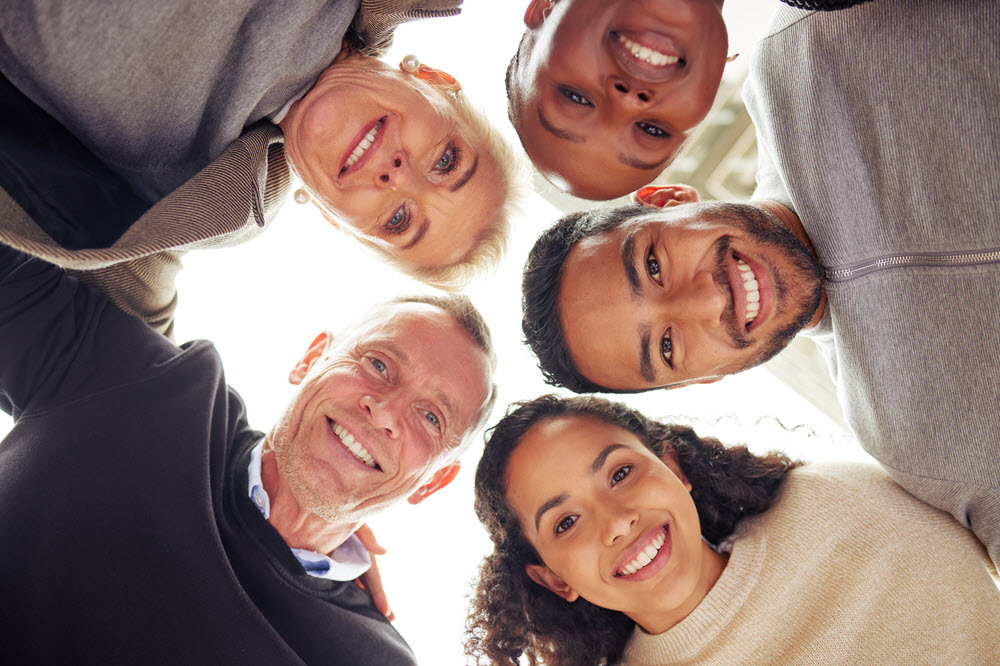 Group of smiling people in a circle looking down at the camera