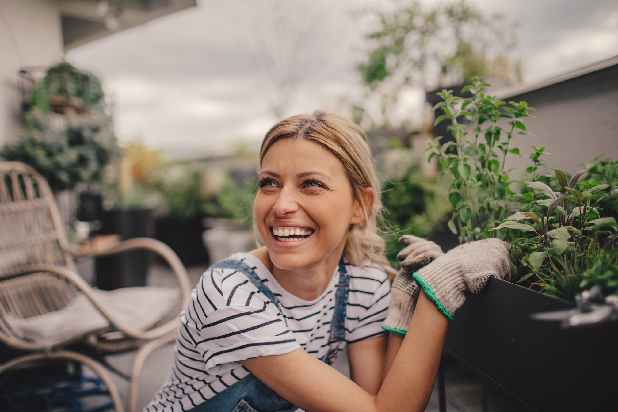 Women on balcony next to a plant pot wearing gloves
